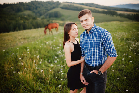 girl is holding the boyfriend of her lover, lovers are standing on the background of a horse and mountains, concept love, dates, a journey together.の写真素材