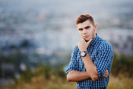 Portrait of a stylish man with a clock in a plaid hipster shirt on a blurred background. copyspaceの写真素材