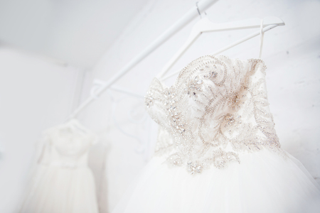 Copy space Wedding dresses for the bride on hangers against a white background of brick in the store. Concept wedding, engagement, attributes, clothing, love.の写真素材