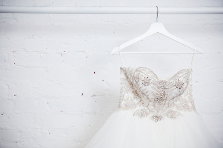 Copy space Wedding dresses for the bride on hangers against a white background of brick in the store. Concept wedding, engagement, attributes, clothing, love.の写真素材