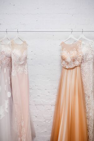 Copy space Wedding dresses for the bride on hangers against a white background of brick in the store. Concept wedding, engagement, attributes, clothing, love.の写真素材