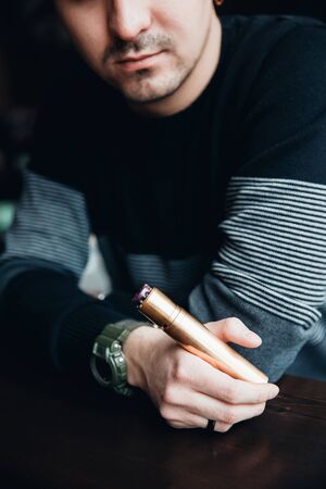 man is holding a phone and smoking a vape. The concept of refusal of tobacco. Vapingの写真素材
