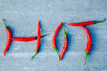 Close-up of chili pepper, inscription HOT on a gray background. The concept of scalding, spices.の写真素材