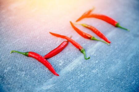 Close-up of chili pepper, inscription HOT on a gray background. The concept of scalding, spices. Blick light.の写真素材