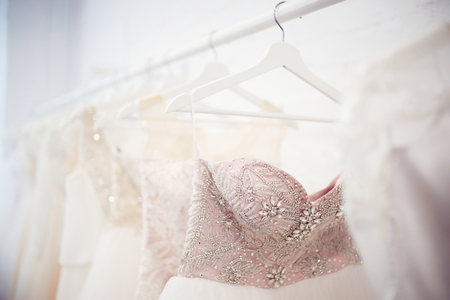 Copy space Wedding dresses for the bride on hangers against a white background of brick in the store. Concept wedding, engagement, attributes, clothing, love.の写真素材