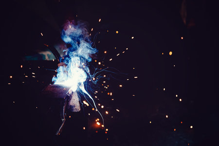 Abstract light flare from the welding machine. Flow of sparks in dark.