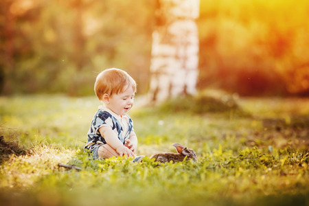Little child boy rejoices rabbit against sunset background, warm light, glare from sun and light. Concept gift for the day of birth.の写真素材