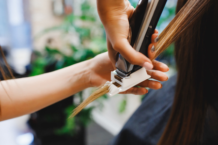 Master performs polishing of split ends of hair for client of girl in hairdresser. concept of hair care, healthy hair.の写真素材