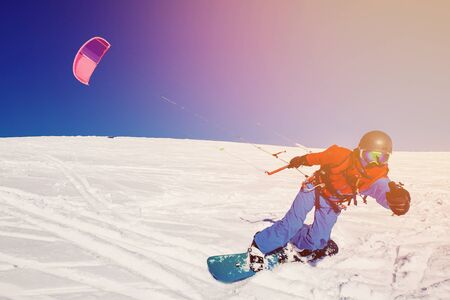Snowboarder with a kite on fresh snow in the winter in the tundra of Russia against a clear blue sky.の写真素材