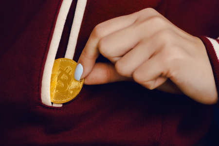 girl folds the bitcoin into her jacket pocket. Concept miningの写真素材