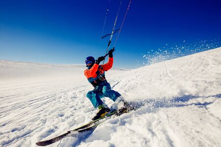 Skier with a kite on fresh snow in the winter in the tundra of Russia against a clear blue sky. Teriberka, Kola Peninsula, Russia. Concept of winter sports snowkite on ski.の写真素材