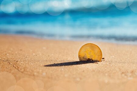 Bitcoin. Bitcoin on golden sand, in background sea. Concept freelance, stock exchange.の写真素材