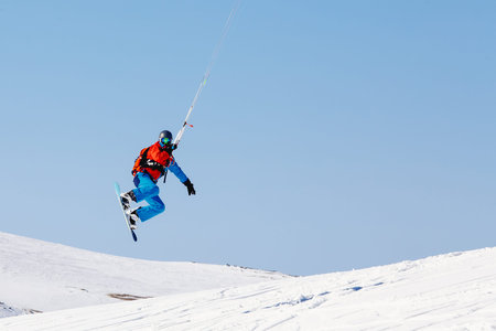 Snowboarder with a kite on fresh snow in the winter in the tundra of Russia against a clear blue sky. Teriberka, Kola Peninsula, Russia. Concept of winter sports snowkite.の写真素材