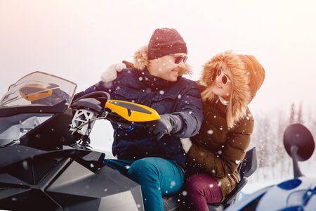 Snowmobile. A couple of girlfriends and a guy on a snowmobile laugh. Concept travel in winter.の写真素材
