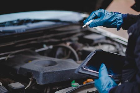 Automechanic conducts diagnostics of the spark plug machine using a tablet computerの写真素材