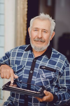 Old man connected on internet with electronic tabの写真素材