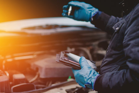 Automechanic conducts diagnostics of the spark plug machine using a tablet computerの写真素材