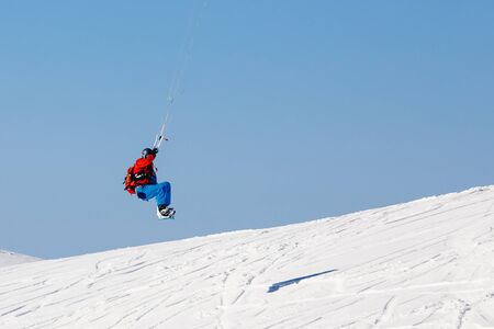 Snowboarder with a kite on fresh snow in the winter in the tundra of Russia against a clear blue sky. Teriberka, Kola Peninsula, Russia. Concept of winter sports snowkite.の写真素材