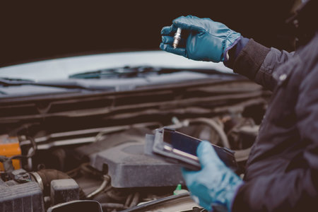 Automechanic conducts diagnostics of the spark plug machine using a tablet computer