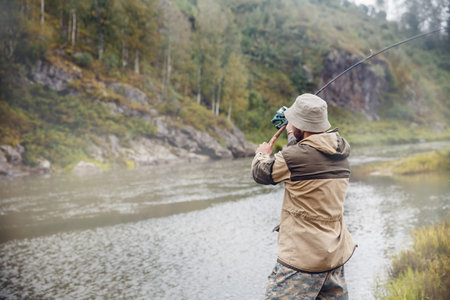 Fishing. The fisherman on a background of rocks throws the fishing rod into the water for catching...