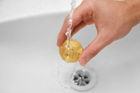 bitcoin. man washes gold coins. Concept money laundering, wash waterの写真素材