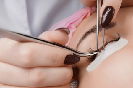 Eyelash extension procedure. Woman with long eyelashes in beauty salon. Lashes close up. Concept spa...
