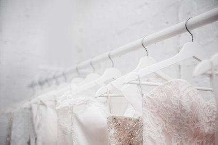 Copy space Wedding dresses for the bride on hangers against a white background of brick in the store. Concept wedding, engagement, attributes, clothing, love.の写真素材