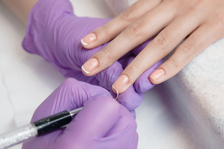 Manicure. Master master does nail delicate French manicureの写真素材