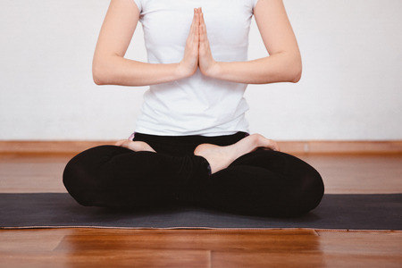 Yoga Concept. Close up woman meditates while practicing yoga in training hall or home.の写真素材