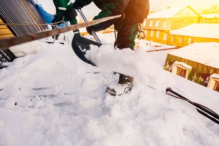 Cleaning roofs of buildings from snow, ice in the winter with a shovel.の写真素材