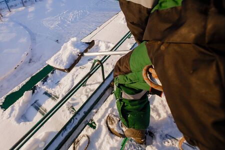 Team of male workers clean roof of building from snow with shovels in securing belts of mantra.の写真素材