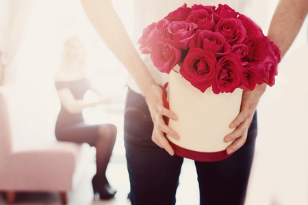 Valentine's Day concept. Man gives bouquet of flowers roses gift in box to girl in love の写真素材