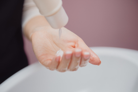 Shampoo hand. Girl master in hair salon squeezes balsam on handの写真素材