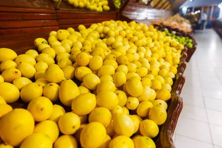 Store bazaar of fresh fruit. Yellow lemons and limes in boxesの写真素材