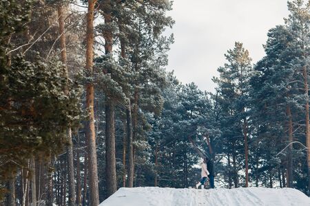 Happy couple having fun, smiling, kissing outdoors in winter against a forest background. Concept people, love, leisure in winterの写真素材