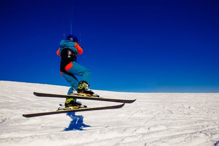 Skier with a kite on fresh snow in the winter in the tundra of Russia against a clear blue sky. Teriberka, Kola Peninsula, Russia. Concept of winter sports snowkite on ski.の写真素材