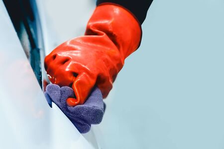Worker hand in glove holds soapy sponge cleaning white car. Concept manual car wash for cars.の写真素材