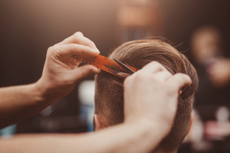 Barber master hairdresser does hairstyle and style with scissors and comb. Concept Barbershop.の写真素材