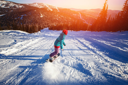 Snowboarder with snowboard rides through snow in forest tramplin. Freeride snowboarding in Sheregesh Ski Resort. sunsetの写真素材