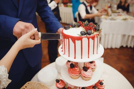 Bride and groom cut wedding cake with fresh flowers rose with knife. Coupの写真素材