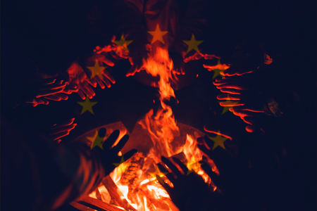 Refugees, illegal immigrants in European Union are warming their hands in fire of barrel fire. European Union flagの写真素材