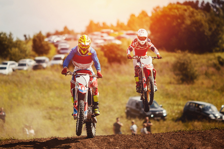 Racer on motorcycle participates in motocross cross-country in flight, jumps and takes off on springboard against sky. Concept active extreme rest.の写真素材