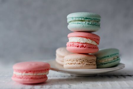 Macaroon. Macaron on gray neutral loft background, stand on plate of different colors: turquoise, pink, beige, wooden background.の写真素材