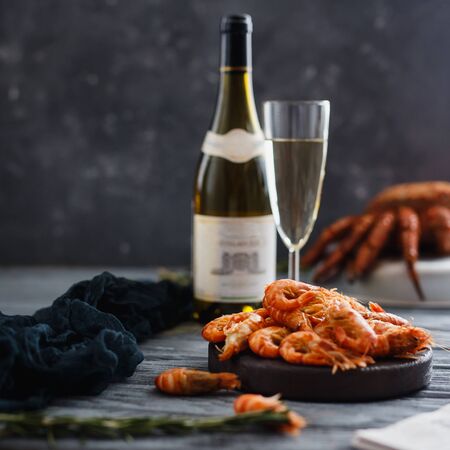 Seafood shrimp. Close-up of ready-made shrimps lie in plate, dark background. In background, crab hairy, bottle of champagne and glass. Concept grilled dinnerの写真素材