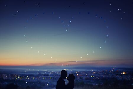 Valentine Day. Silhouette of couple in love against background of night city, stars and horizon. Concept is date on roof, first loveの写真素材