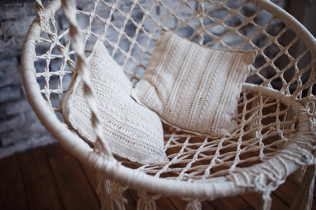 Armchair hanging. Design of a swing for the house from ropes and a rope with white pillowsの写真素材