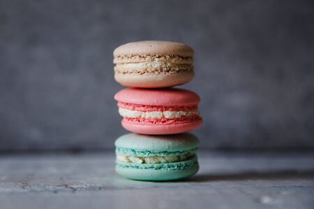 Macaroon. Macaron on gray neutral loft background, stand on plate of different colors. Wooden background.の写真素材