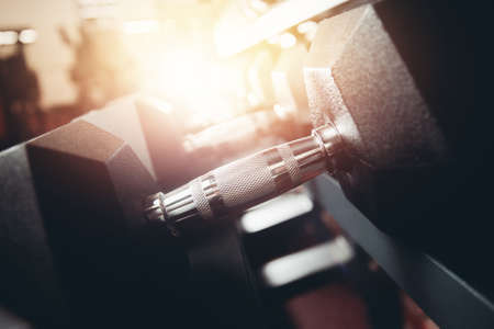 Lot of dumbbells stand in row in gym, glare of light. Concept slimming, musculature, bodybuilding, Sports Equipment.の写真素材