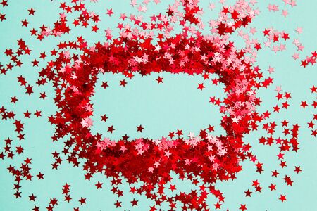 Confetti. Frame made of colored red star confetti front of blue background. Copy spaceの写真素材
