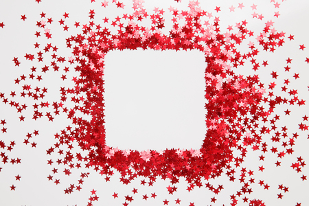 Confetti. Frame made of colored red star confetti front of white background. Copy spaceの写真素材